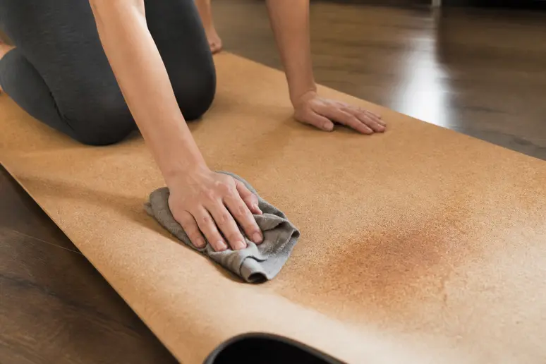 Nettoyage d'un tapis de yoga en liège avec un chiffon doux et de l'eau pour l'entretien régulier.