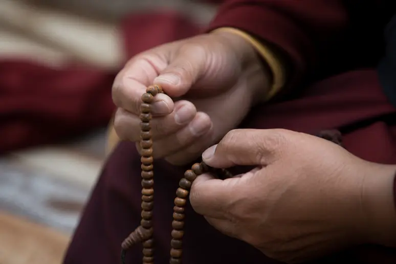 Mains faisant glisser les perles d un collier mâlâ lors de la méditation