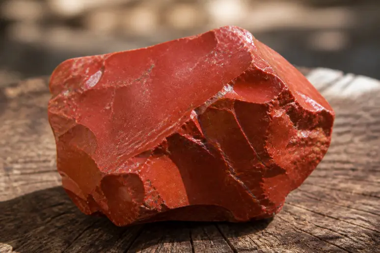 Pierre de jaspe rouge brute posée sur une surface en bois pour l ancrage