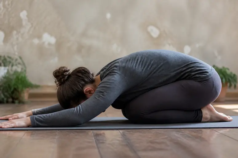 Pratique de la posture enfant relaxation avec les genoux écartés et le bassin détendu sur un tapis
